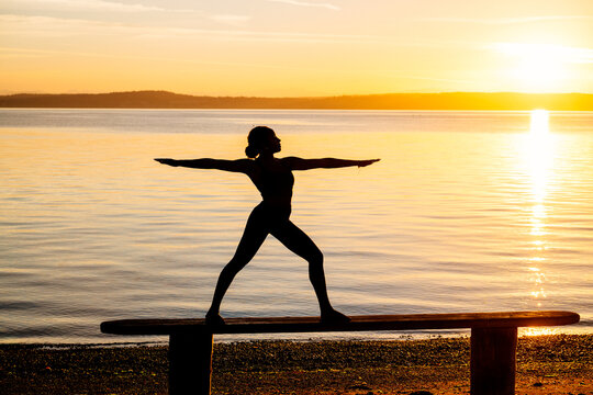 Hispanic woman practicing yoga warrior pose balancing on a bench
