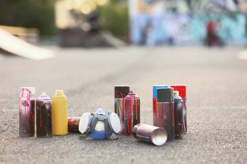 Street art and urban culture, spray paint cans and respirator mask on asphalt ground for graffiti artist creative expression and mural design project © Pixel-Shot