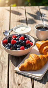 A rustic wooden table outdoors features a bowl of fresh berries, yogurt, crispy croissants, and coffee under the warm morning sunlight, foliage, summer, leaves