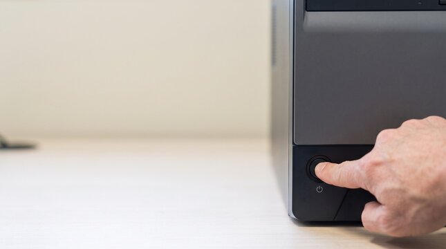 不具合でパソコンの電源ボタンを押す会社員の手