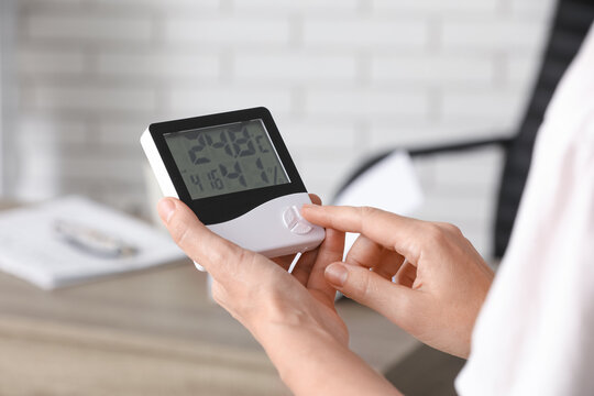 Energy efficiency and climate control, person adjusting digital thermometer for home comfort and indoor air quality monitoring in a modern office