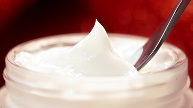 Silver Spatula Scooping Luxury White Skincare Face Cream Frosted Jar Smooth Texture Macro Close Up Red Bokeh Background Beauty Cosmetic Commercial Video