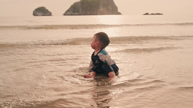 Toddler enjoying water play at beach shore during warm sunset family vacation.