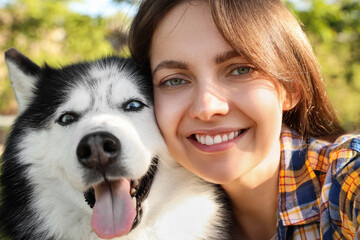 Pet companionship and animal therapy, happy woman hugging her siberian husky dog outdoors in a park during a sunny day for a lifestyle portrait © Pixel-Shot