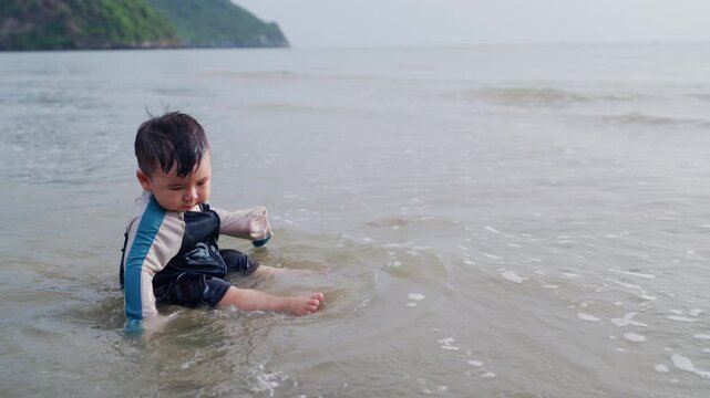 Toddler enjoying water play at beach shore during warm sunset family vacation.