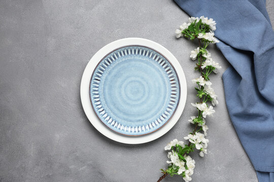 Beautiful table setting with white blooming branch and napkin on grey grunge background