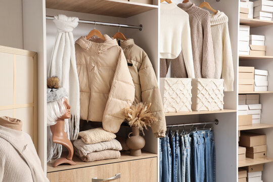Hangers with different winter clothes in wardrobe