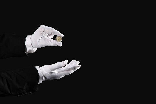 Male magicians hands with coin on black background