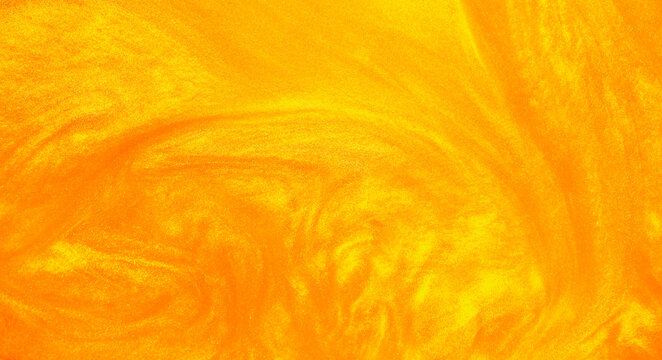 Shimmering gold abstract background. Liquid gold texture waves and swirls. Beautiful shiny yellow texture with glitter. Liquid gold metallic paint close-up.