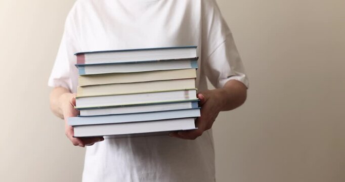 Person holding a stack of books, person holding a stack of books, book theme, reading theme, lifestyle theme
