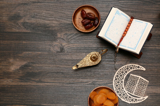 Aladdin lamp, Koran, dates and dried apricots on wooden background. Ramadan celebration