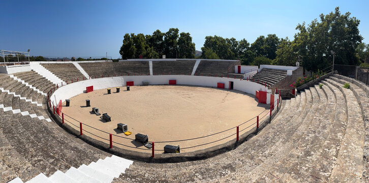 Interior of the plaza de toros bullring in Alc&uacute;dia, on the island of Mallorca, Balearic Islands, Spain, showing the sand-covered arena floor and tiered concrete seating with red railings.