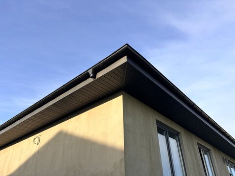A view of a house under construction with a finished roof at sunset