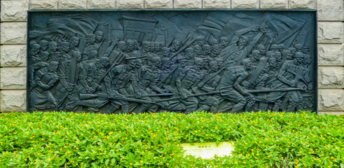 Historic uprising bronze relief mural on stone wall in China © DinhThi