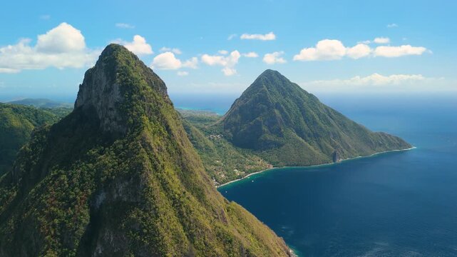 Slow rightward pan reveals Petit and Gros Piton peaks side by side above coastal village and blue sea