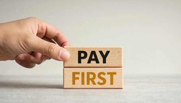 Hand placing wooden block with pay first text for financial priority concept on neutral surface