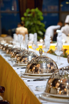 Elegant banquet table with covered serving dishes and glassware