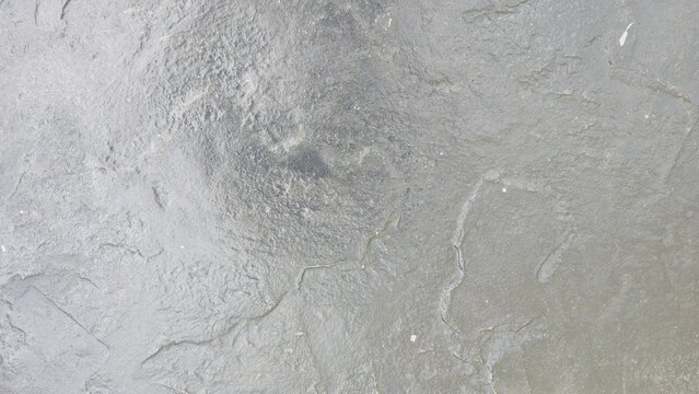 Old grey concrete floor with cracks and natural stains. Industrial loft grey cement floor texture backdrop. Raw grey concrete surface with distressed texture, perfect for modern design backdrops. 