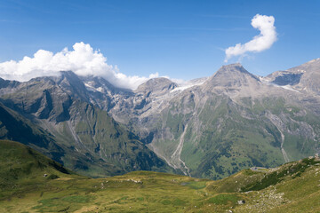 Obraz premium Panoramic View of Alpine Mountains with Green Valleys under Blue Sky on a Sunny Day