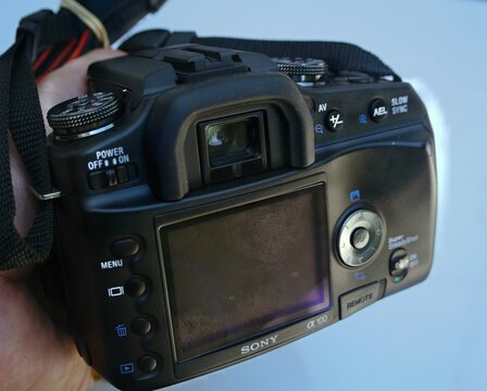 Hand holding Sony &alpha;100 DSLR camera controls