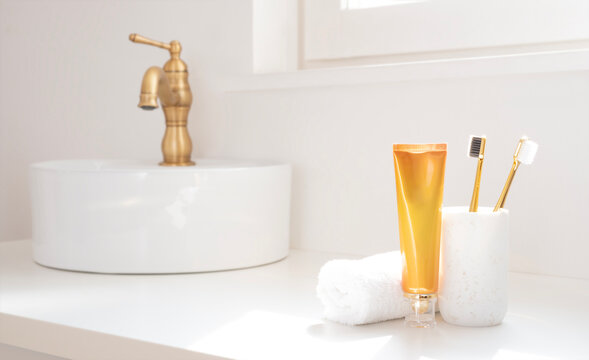 Bathroom clean vanity with white vessel sink, bronze faucet, toothpaste with toothbrushes and folded spa towel