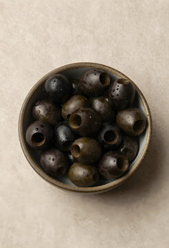 Mediterranean diet and healthy nutrition, pitted black olives in a ceramic bowl for culinary preparation and gourmet food ingredients on stone surface