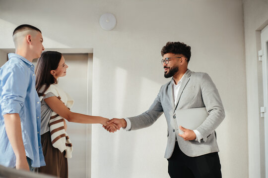 Real estate agent shaking hands with couple
