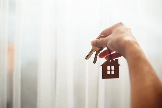 Hand holding house keys with home keychain