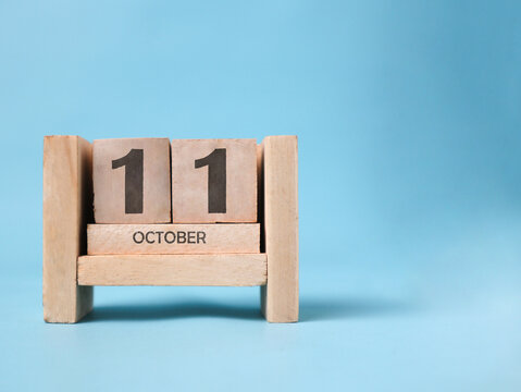 A wooden block calendar for October 11th on a light blue background