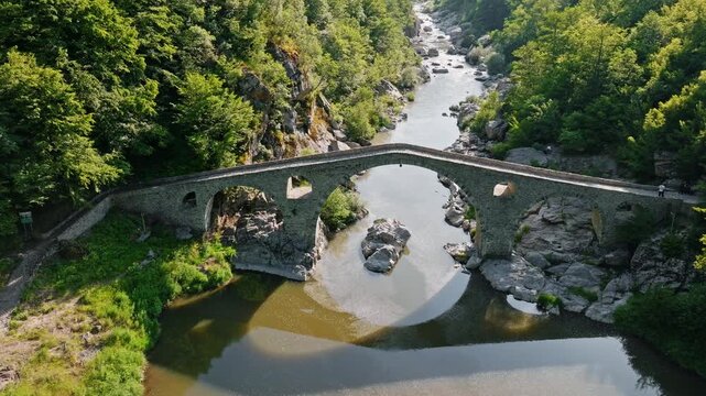 Aerial view tourists walking Devils Bridge ancient Ottoman stone arch bridge Arda river Rhodope mountains Bulgaria travel vacation destination hiking scenic landscape