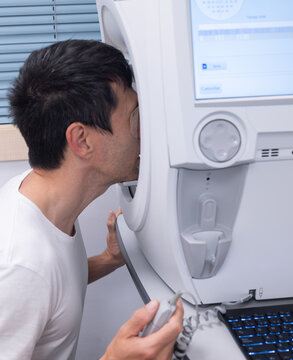 Man testing his visual field on an ophthalmology machine for eye diagnosis
