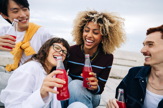 Friends laughing together while sharing drinks outdoors