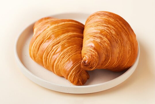 Freshly baked croissants on a beige plate stacked. Side view