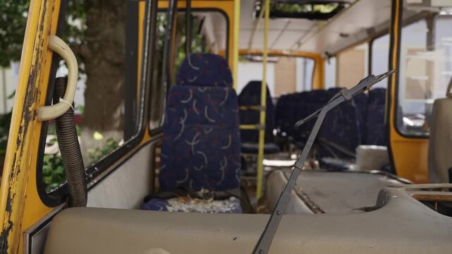 Close-up shot of windshield wipers against the backdrop of the damaged interior of a yellow bus&mdash;missing its windshield&mdash;that was involved in an accident. The damaged school bus is parked in an impound 