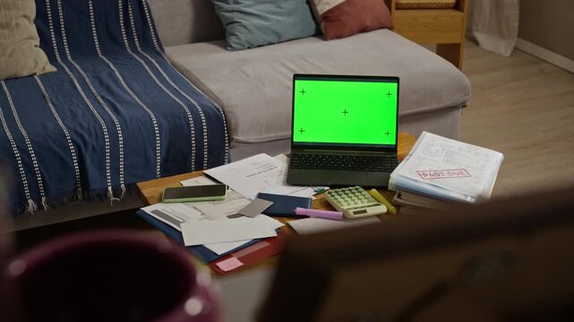 Laptop with green screen sitting on table surrounded by unpaid bills, calculator, and past due folder. Footage is ideal for financial planning, debt relief, or online banking commercials