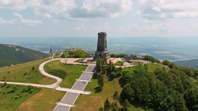 Panoramic aerial view Shipka Monument Liberty stone tower stairs pathway Balkan mountains valley background sunny day Bulgaria travel destination historic landmark drone