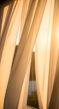 Soft white curtains hanging in front of a window with warm golden hour sunlight shining through