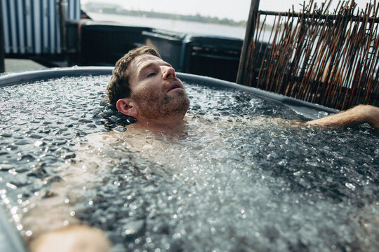 A wellness-minded man sits in ice water for recovery and cold therapy.