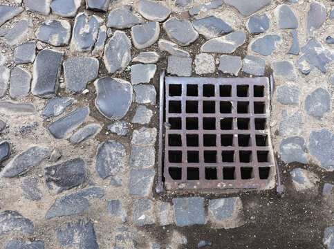 Old iron grate on paving stones