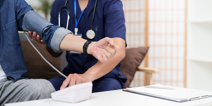 Male nurse checking blood pressure of senior patient at home