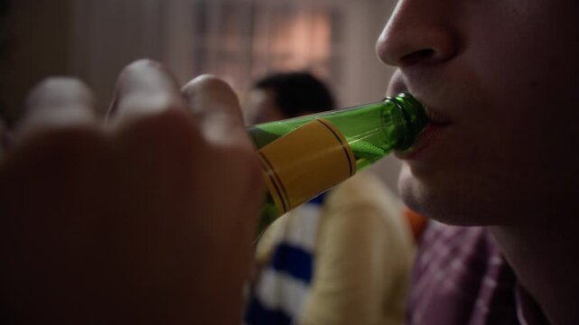 Caucasian young adult man opening beer bottle and drinking while watching sports with diverse friends at home. Perfect for beverage commercials, streaming service ads and fan lifestyle promos