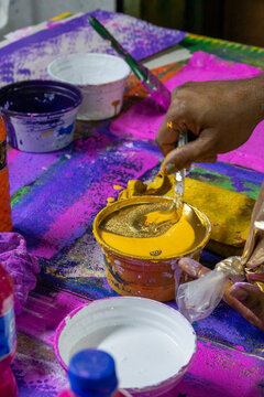 Close-up of a hand mixing golden dye paste for hand block printing, Dhaka Division, Dhaka, Bangladesh