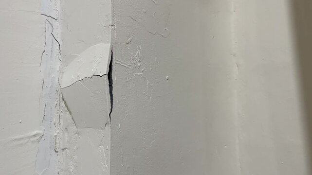 Close up view of severe wall crack and broken corner plaster