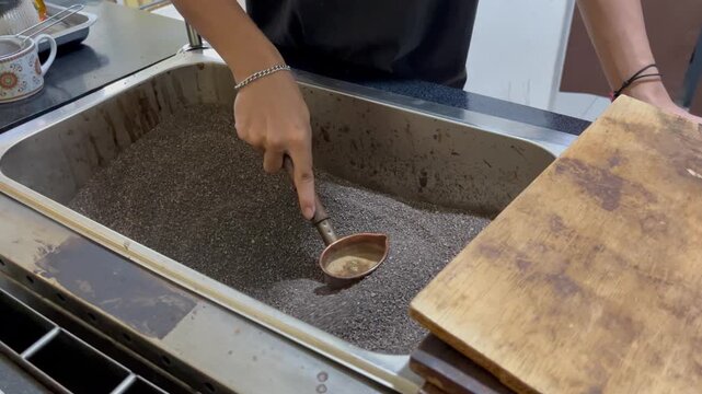 Person using a ladle to scoop liquid from a kitchen sink.