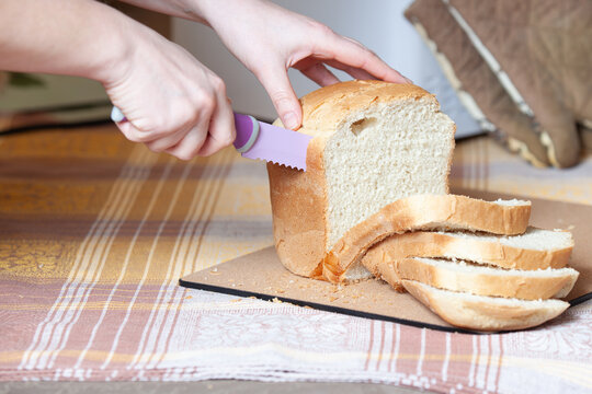 woman hands slice fresh bread slices with knife
