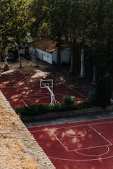 Two empty basketball courts with hoops are seen from above beside trees and old brick walls in Kalemegdan. Urban sport, fitness, recreation and public space concept. © Ekaterina