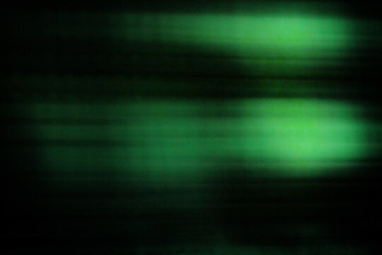 Against a dark background, two flashes of greenish fluorescent light leave trails of light in their wake