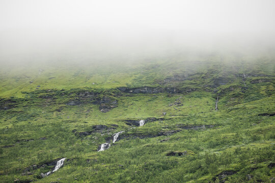 Waterfalls Cascading Through a Foggy Green Mountain Valley