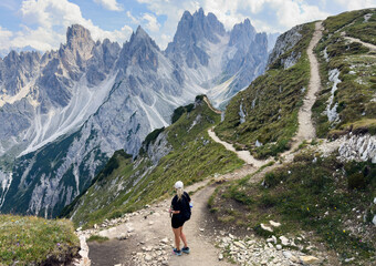 Fototapeta premium Young woman exploring hiking trail in Dolomites near Tre Cime