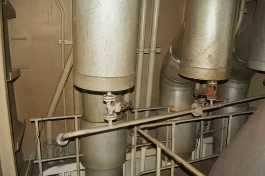 heavy industrial piping with thermal cladding insulation, shutoff valves, and metal guard railings inside a marine engine room